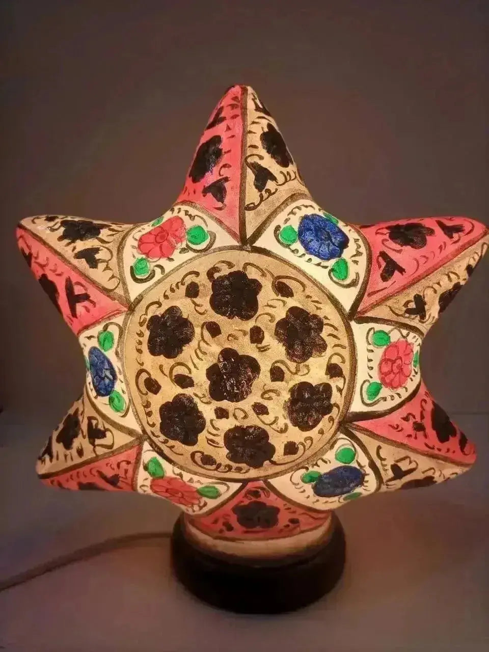 Hand-painted star shape camel skin lamp with intricate multicolor art in pink black blue green and cream tones on ceramic base